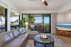 Relax in this stylish living room with a large coffee table, comfortable sofa, and sliding glass door leading to an ocean view.
