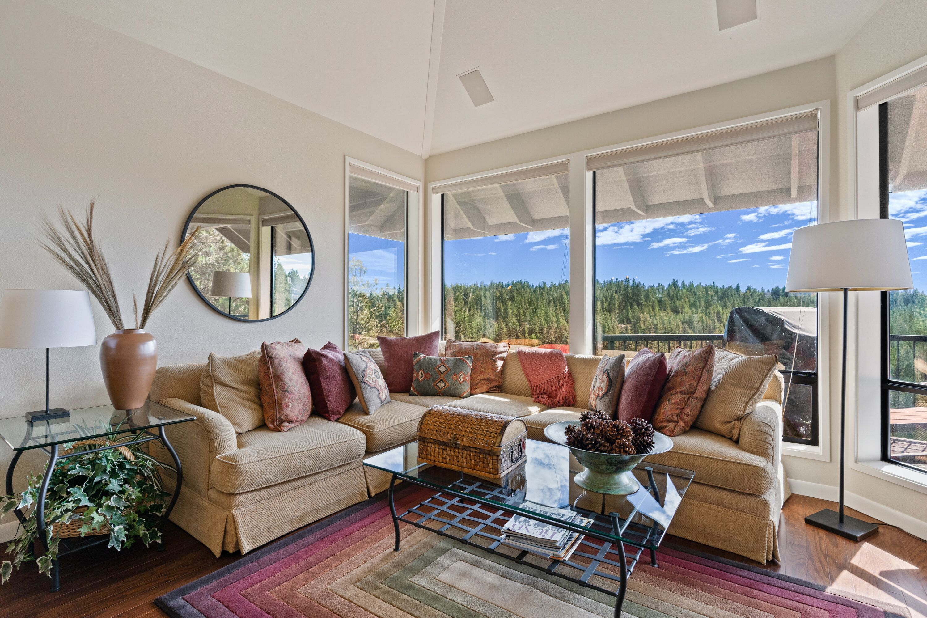 A spacious living room with a large window offering a view of a forested area.