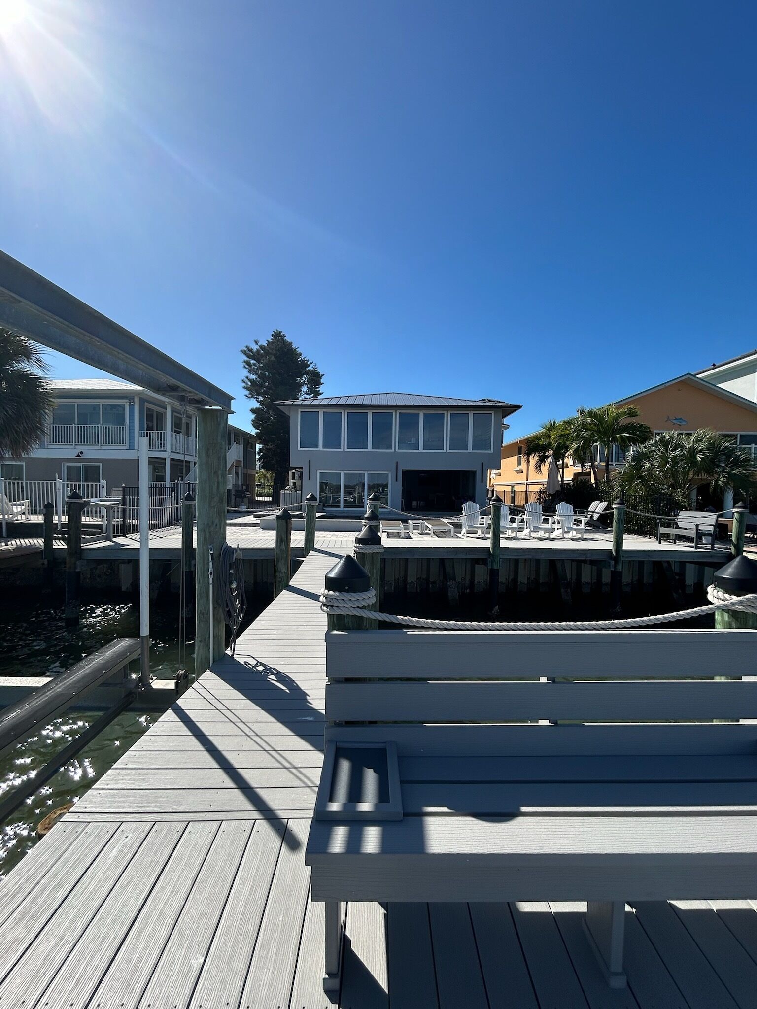A wooden dock with a bench, a clear sky, and buildings in the background.