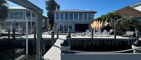 A wooden dock with a bench, a clear sky, and buildings in the background.