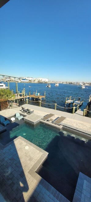 A marina with boats, a dock, and a pool area with lounge chairs and a hot tub. - Amazing Bay Views, Pool, Private Boat Dock, Walking Distance to Times Square (Fort Myers Beach)