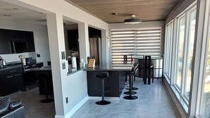 Een ruime, open leefruimte met keuken, bar en zitgedeelte.