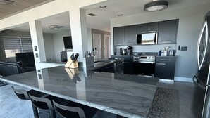 Een moderne keuken met een groot schiereiland, barkrukken en roestvrijstalen apparatuur.