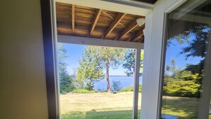 A door leading to a covered outdoor area with a view of a grassy yard and a tree.