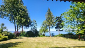 A grassy yard with a view of the water and trees.