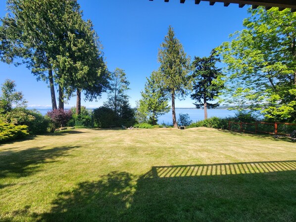 A grassy yard with a view of the water and trees. - Pet-friendly Waterfront Cottage With Beautiful Views, Huge Yard, Mooring Buoy (Lummi Island)