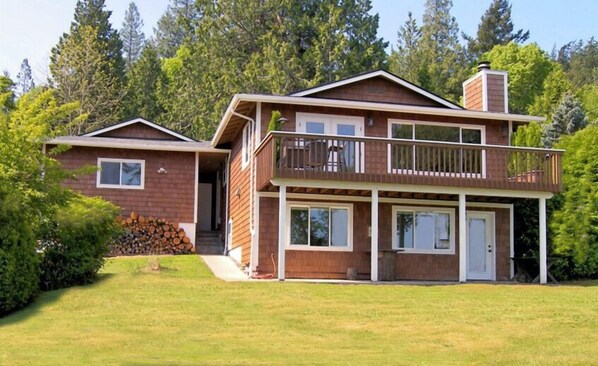 A two-story house with a balcony and a covered porch. - Pet-friendly Waterfront Cottage With Beautiful Views, Huge Yard, Mooring Buoy (Lummi Island)
