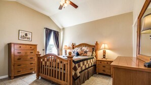 Une chambre à coucher avec un lit en bois, une table de chevet, une commode et un ventilateur de plafond.