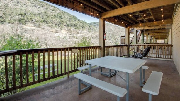 Une terrasse extérieure avec une table et des bancs, offrant une vue sur un paysage vallonné.