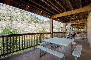 Une terrasse extérieure avec une table et des bancs, offrant une vue sur un paysage vallonné.