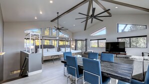 Een modern interieur met een eethoek, bank, televisie en grote ramen.