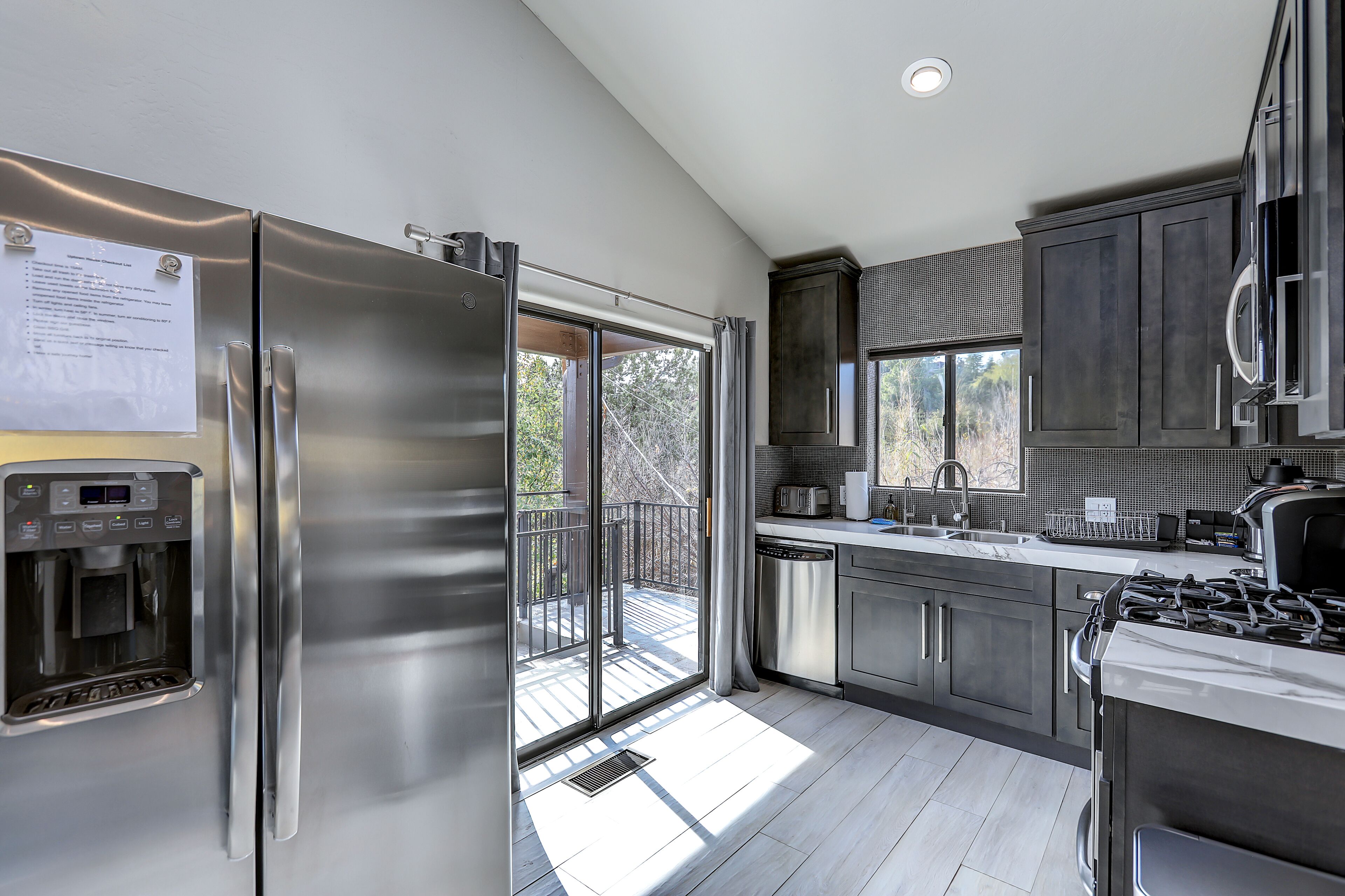 A modern kitchen with stainless steel appliances, a water dispenser, and a view to the outside.