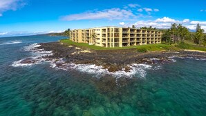 Un hotel de varios pisos con diseño circular, ubicado en una isla rocosa rodeada de aguas azules cristalinas.