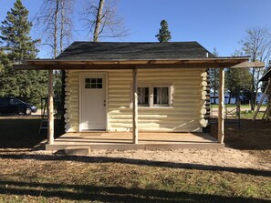 A log cabin with a front door, a small porch, and a window. - Cabin #1 Near Beautiful Brevort Lake (Moran)