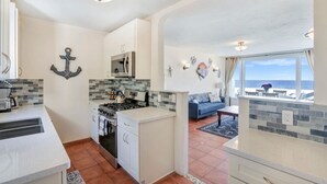 Cocina compacta con estufa a gas, microondas y un pequeño comedor con un sofá azul.