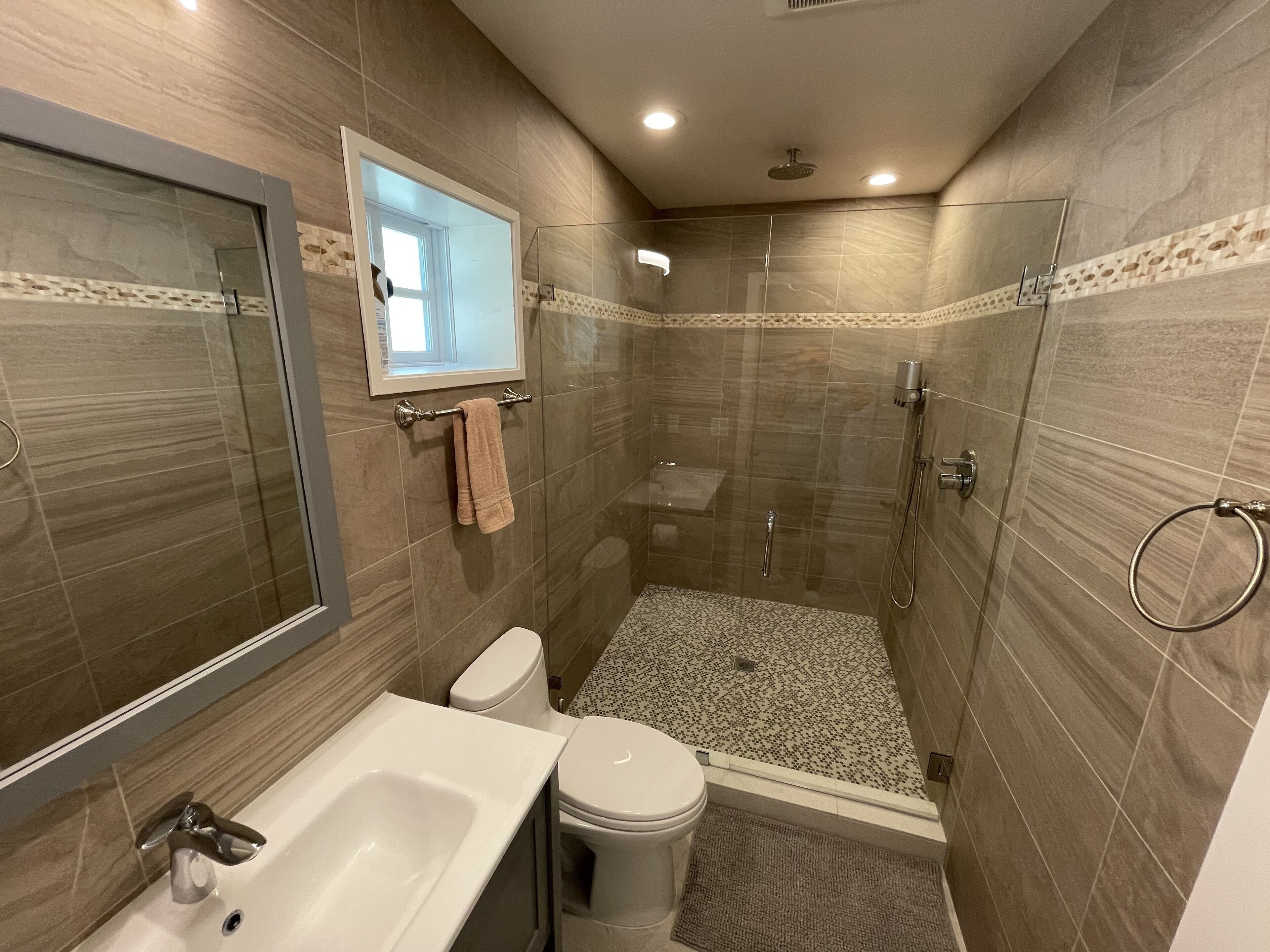 Uma casa de banho moderna com chuveiro, sanita e lavatório.