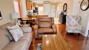 A living room with a brown leather chair, a patterned sofa, and a wooden coffee table.