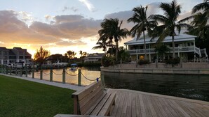 A waterfront property with a dock, a boat, and a building with a balcony overlooking the water.