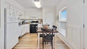 Una cocina con armarios blancos, una mesa de comedor de madera y un microondas.