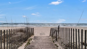 Un sendero de madera que lleva a una playa, con una valla de madera a ambos lados.