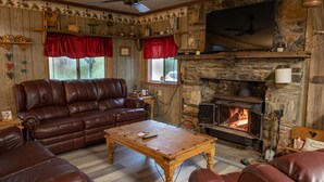 A cozy living room with a stone fireplace, leather sofas, and a wooden coffee table.