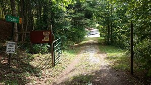 A dirt path leading to a building with a sign indicating it's a private road.
