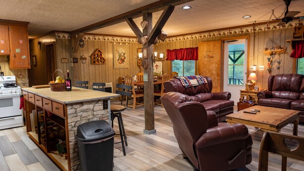 A cozy living room with a fireplace, leather sofas, and a dining area with wooden furniture.