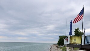 En strand med ett staket, en flagga och utsikt över havet.