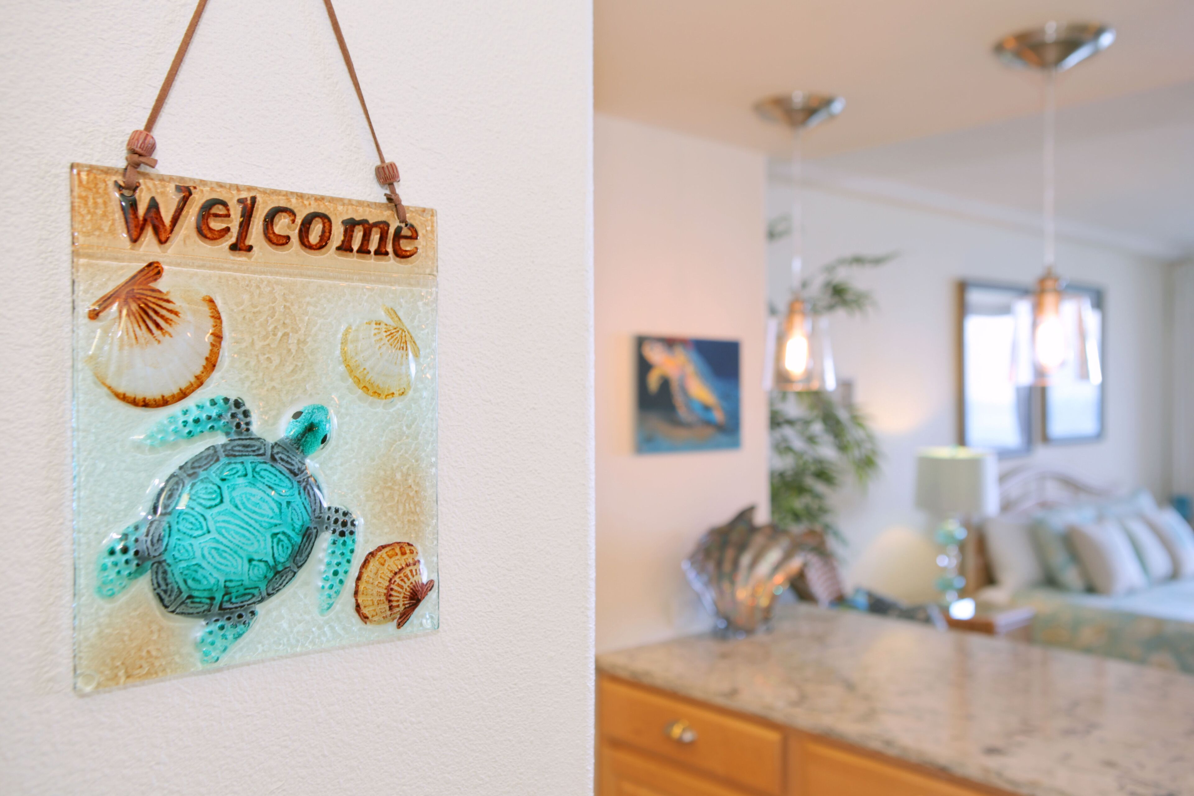 Een welkomstbord met zeedieren en een moderne keuken met een marmeren aanrecht en hanglampen.