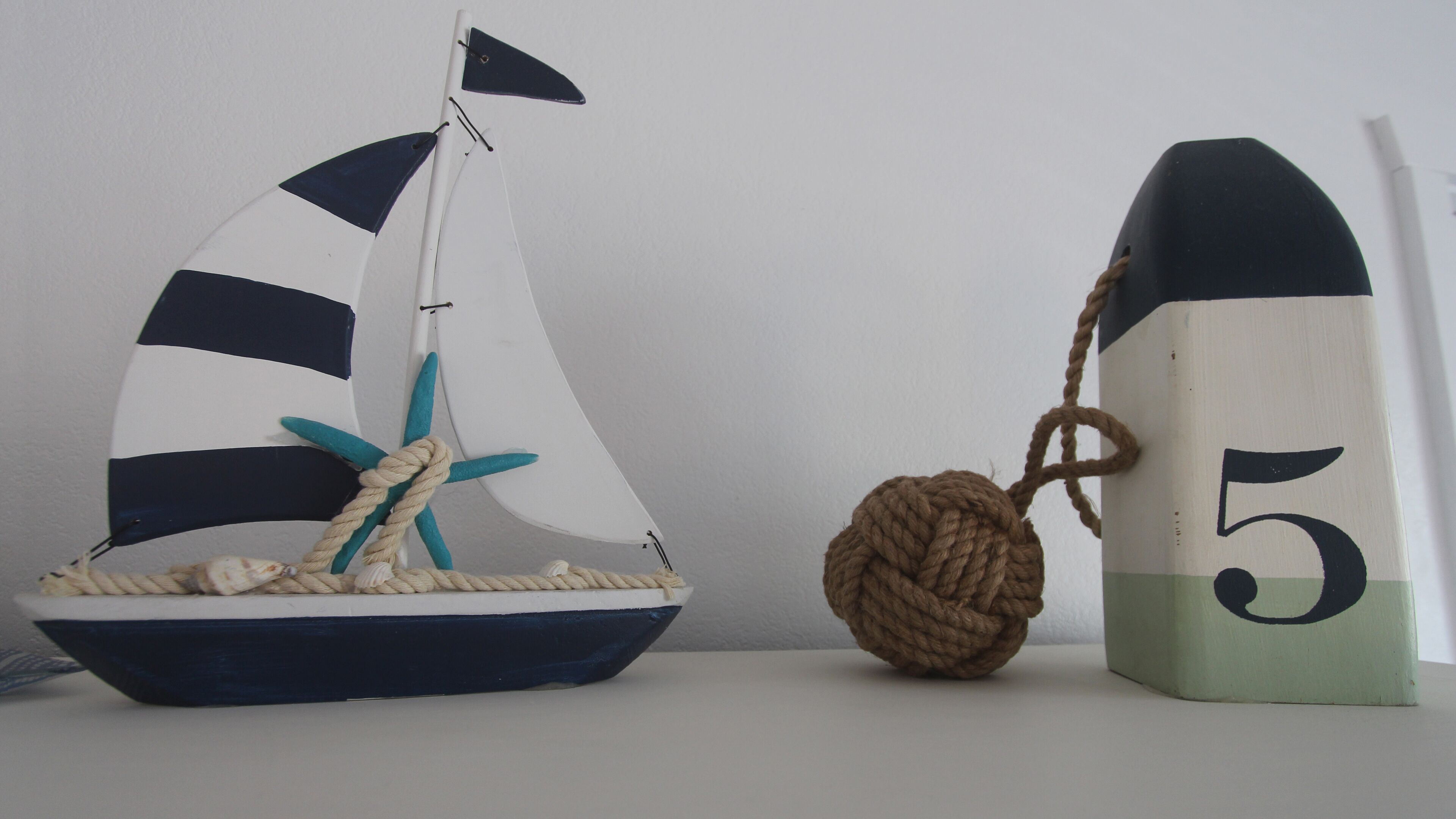 A model sailboat with a star and a rope ball next to a block with the number 5 on it.