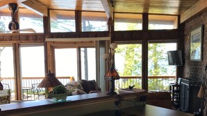 Une cuisine dotée d’un grand îlot central, de poutres en bois au plafond et de grandes fenêtres.
