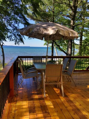 Enjoy a serene view of the water from this outdoor deck, surrounded by lush trees and a comfortable seating area.