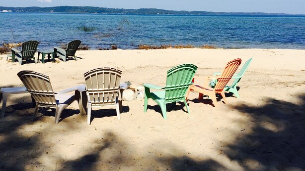 Une plage où plusieurs chaises Adirondack sont disposées sur le sable, face à l’océan.