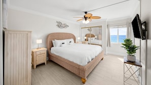 Ein Schlafzimmer mit einem großen Bett, einem Deckenventilator, einem Nachttisch, einer Stehlampe, einer Topfpflanze und Meerblick.