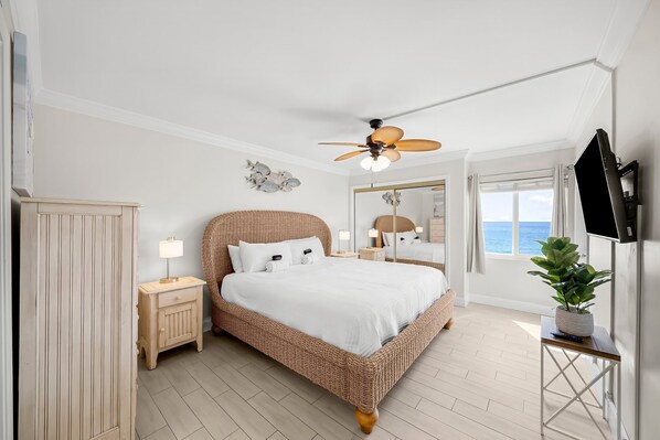 A bedroom with a large bed, a ceiling fan, a nightstand, a bedside table, a potted plant, and a view of the sea. - Beach Front, Corner Unit Condominium on the 6th Floor. Incredible Beach View! (Destin)