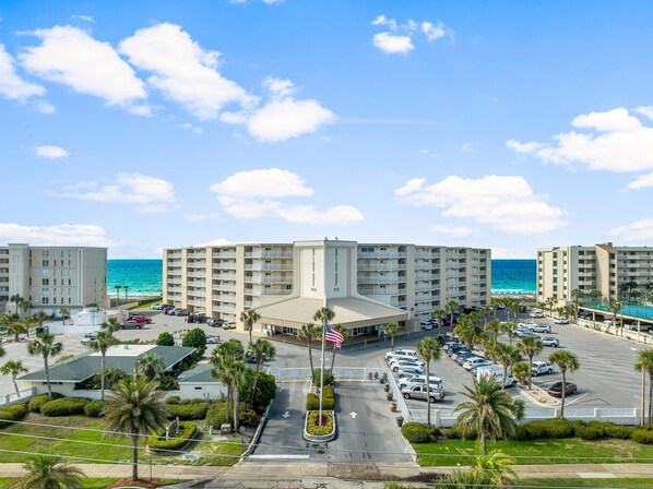 A hotel with multiple floors, a parking lot, and a view of the ocean. - Beach Front, Corner Unit Condominium on the 6th Floor. Incredible Beach View! (Destin)