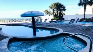 Un espace piscine doté d’un jacuzzi, de chaises longues et d’un palmier.