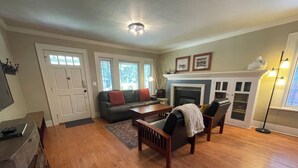 A living room with hardwood flooring, a sofa, a coffee table, and a fireplace. - Historic Downtown │Walk Everywhere │Private Hot Tub │One Block to River (Bend)