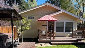 A single-story house with a covered patio, a barbecue area, and a red umbrella. - Historic Downtown │Walk Everywhere │Private Hot Tub │One Block to River (Bend)