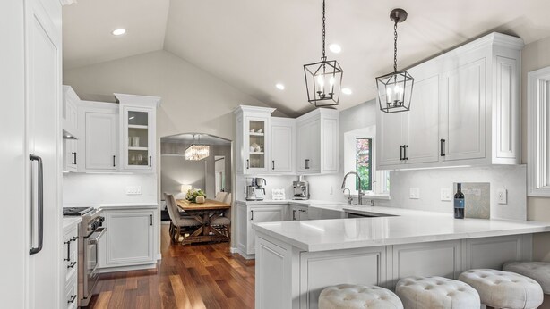 Une cuisine moderne avec des meubles blancs, un grand îlot central et des tabourets en bois.