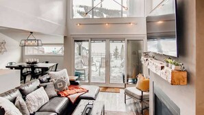A modern living room with a sofa, television, and a fireplace. - True Ski/Golf-in,Ski-Out Luxury Modern with Views (Frisco)