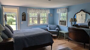 Une chambre à coucher avec un lit, une chaise, une commode et une fenêtre avec des rideaux.