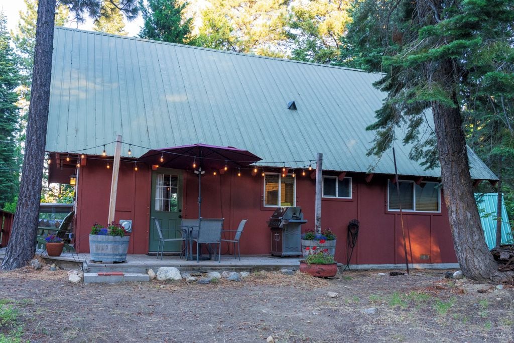 A red building with a metal roof, outdoor seating, and string lights.