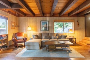 A cozy living room with a sectional sofa, a wooden coffee table, and a bookshelf. - Charming West Shore Chalet, Great Location, Close to the Lake, Hiking and Biking (Tahoma)