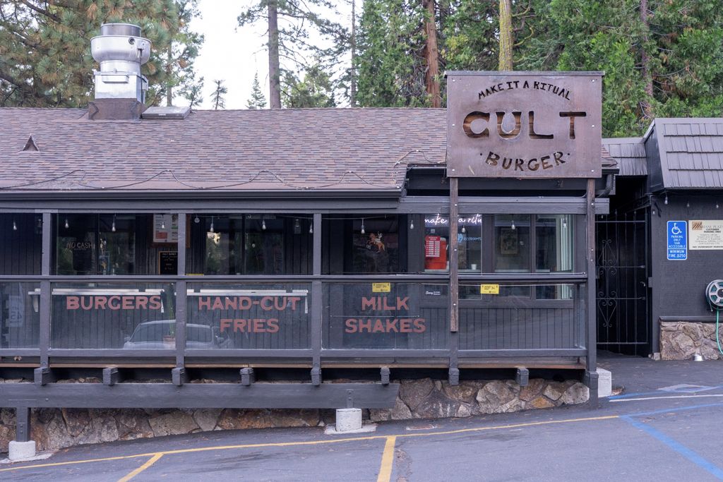 Ein rustikales Restaurant mit einem Schild, auf dem 'MAKE IT A RITUAL CULT BURGER' steht.