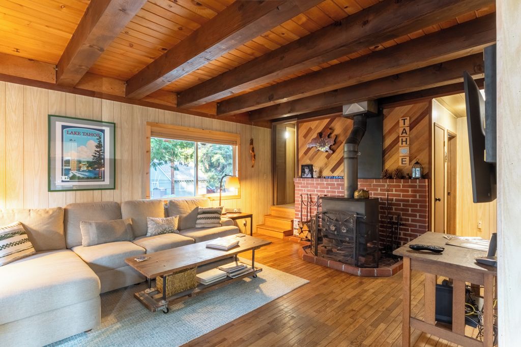 Uma sala de estar acolhedora com lareira, vigas de madeira e uma fotografia emoldurada do Lago Tahoe.