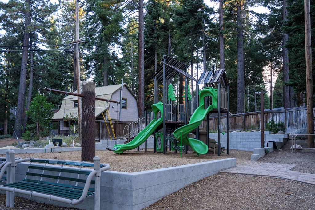 Un parc infantil amb tobogans verds i una cadira.