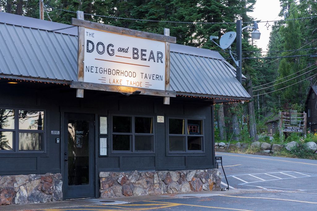 Paikallinen pub, jossa on kyltti, kivinen perustus ja metallikatto.