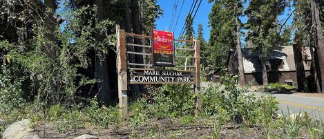 A wooden sign with the text "Marie Sluchak Community Park" and a red poster advertising "The Beatles" event.