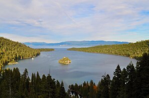 Un llac envoltat de bosc dens, amb una petita illa al centre i muntanyes al fons.